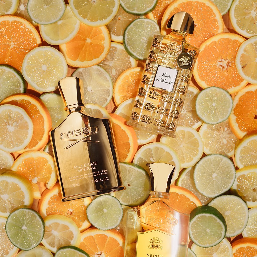 Frascos de perfume Creed Millésime Impérial, Creed Jardin d'Amalfi y Creed Neroli Sauvage sobre una cama de rodajas de cítricos.